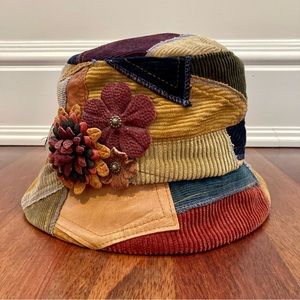 Corduroy and leather patchwork bucket hat with flower appliqué.